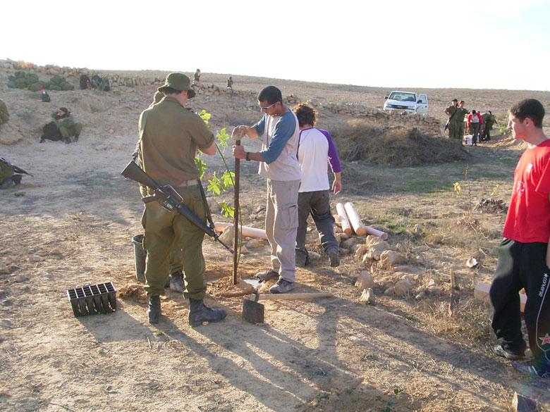 Israeli IDF soldiers serving in the desert on duty in the Negev, help to rejuvenate the Negev ancient agricultural installations with a high schooler at Nitzana. The soldiers join with the high school students and staff to help plant new trees. 