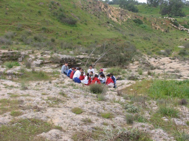 Field lecture at Ofaqim. Located 20 kilometers northwest of Beer Sheva, this is the Merchavim School. Students here are shown measuring and surveying an ancient agricultural site from the Byzantine Period, which consists of ruins of a farm house and several water cisterns and an ancient agricultural terrace.