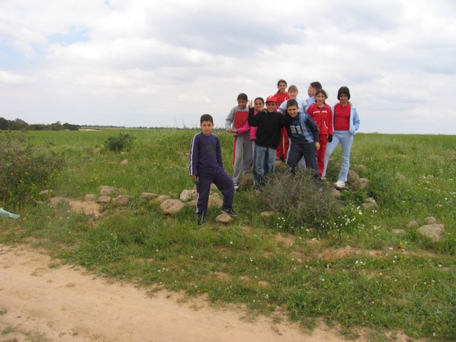 Class on top of the Byzantine ruin at Ofaqim. Located 20 kilometers northwest of Beer Sheva, this is the Merchavim School. Students here are shown measuring and surveying an ancient agricultural site from the Byzantine Period, which consists of ruins of a farm house and several water cisterns and an ancient agricultural terrace.